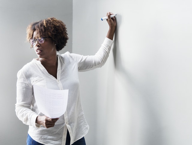 A women of a minority group teaching at a whiteboard