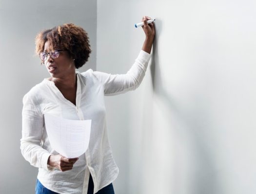 A women of a minority group teaching at a whiteboard