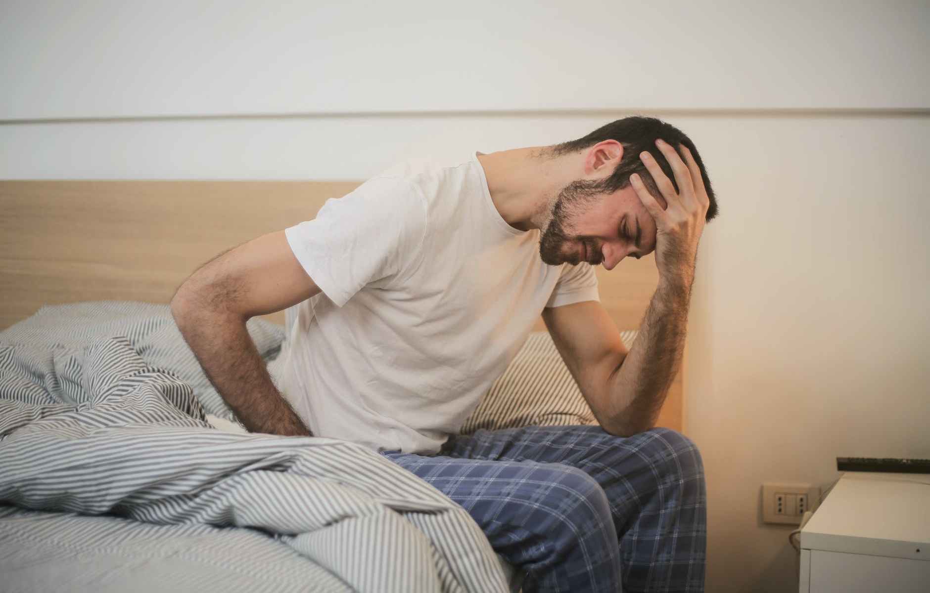 young man in sleepwear suffering from headache in morning